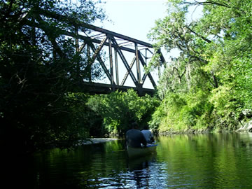 Canoers going underneath an antique railroad bridge